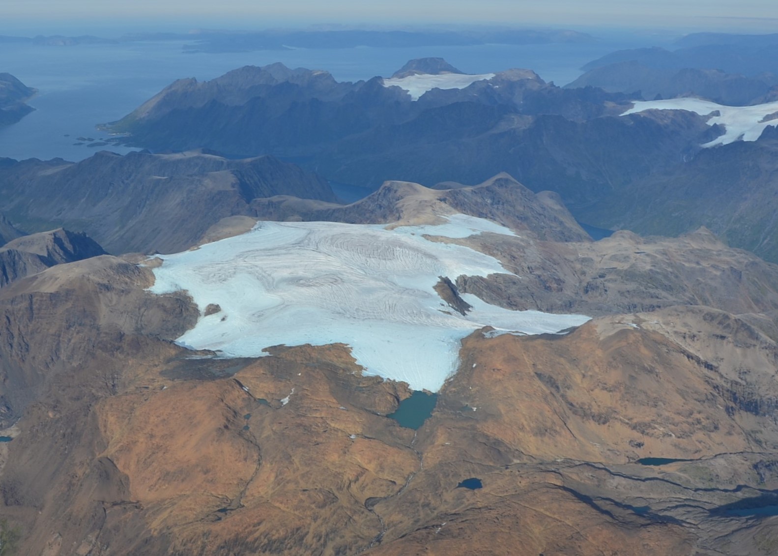 Langfjordjøkelen 29. august 2024. I bakgrunnen ses to andre breer i Vest-Finnmark, Svartfjelljøkelen til venstre og den vestlige delen av Øksfjordjøkelen til høyre.  Foto: Flytjenesten i Tromsø.